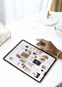 A woman's hand next to an iPad on a white desk with white accessories